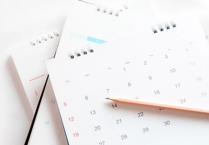 Calendriers papier posés sur une table illustrant la planification de campagnes SMS marketing avec Odoo